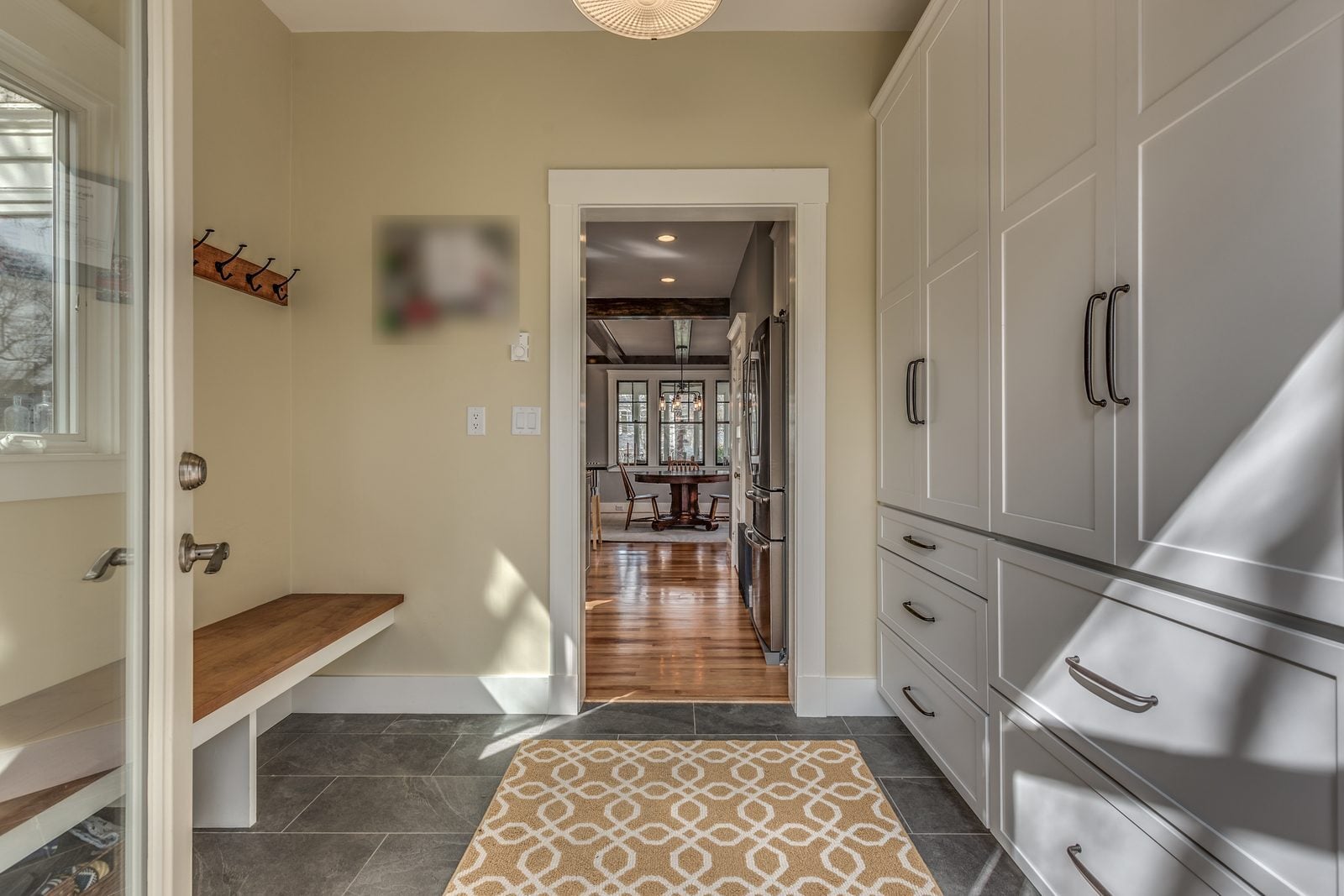 Mudroom bench and coat hooks with a doorway into the kitchen