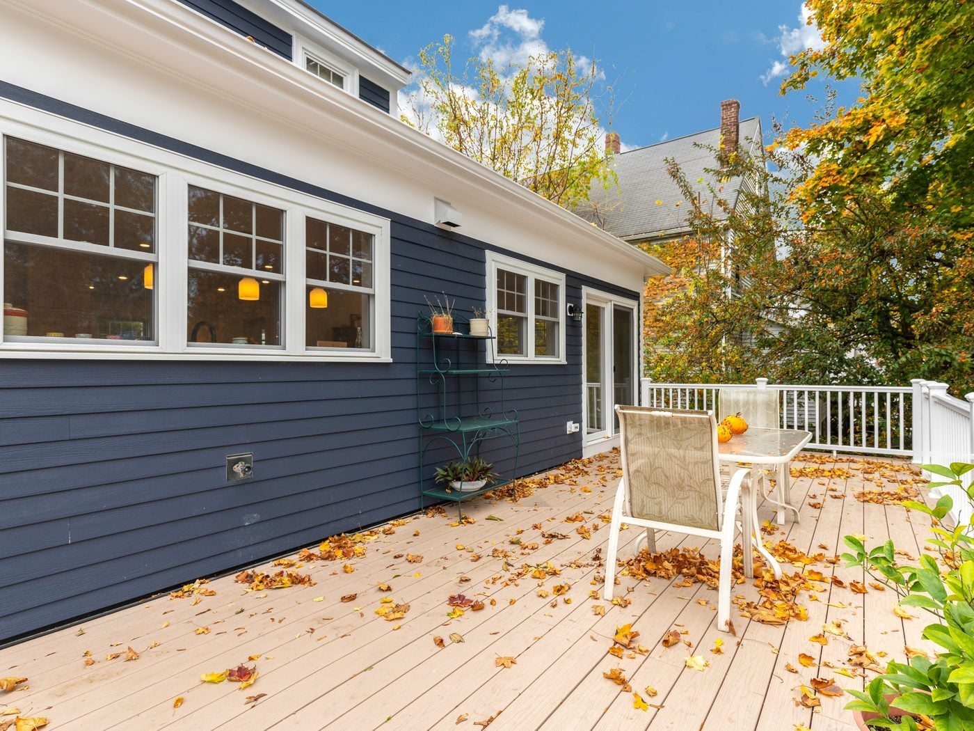 After: Back of the house: the old back door and painted deck gave way to a single-story addition with a wall of windows, a slider, new siding and a wide composite deck.