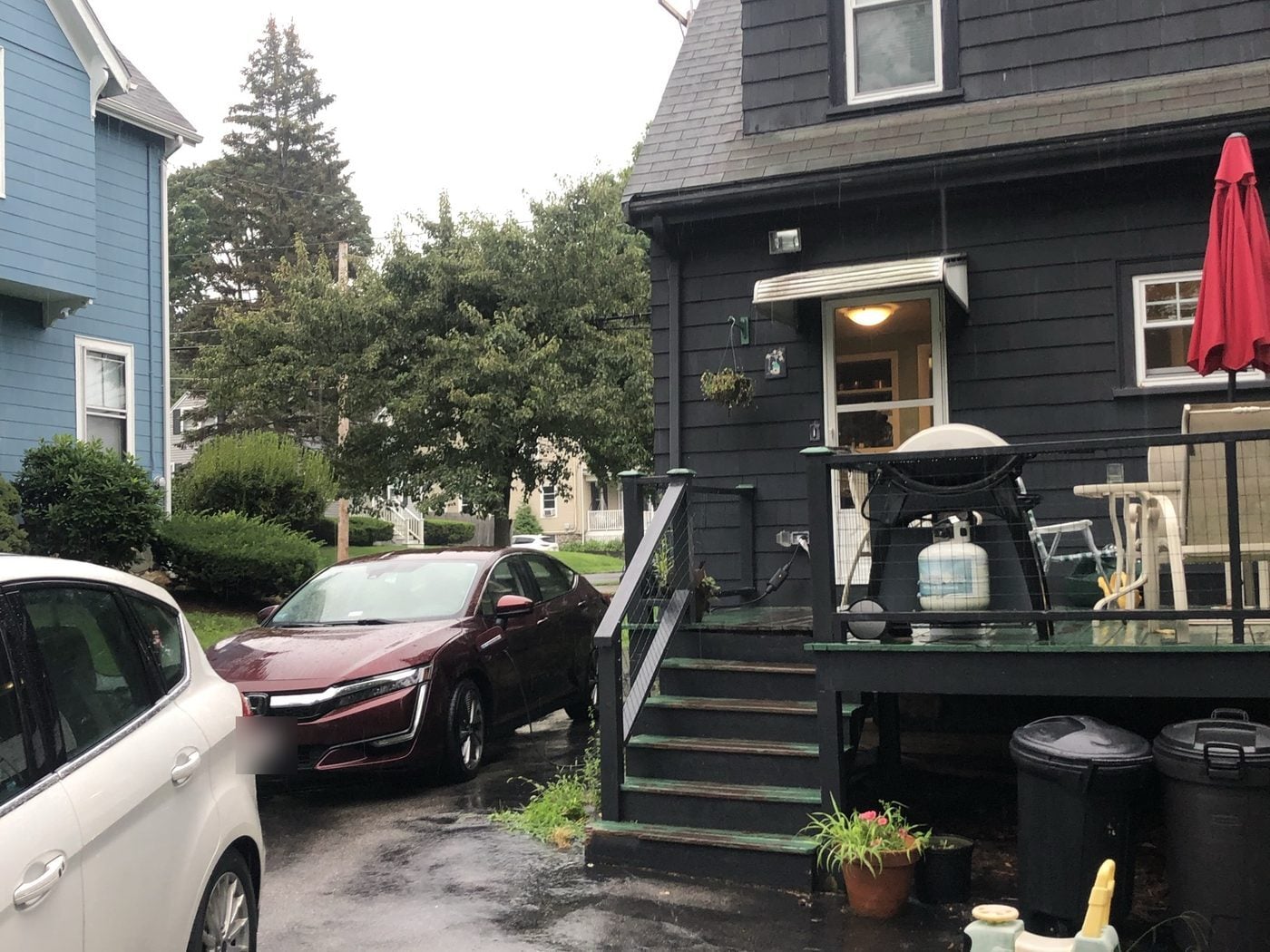 Before: Back of the house: the old back door and painted deck gave way to a single-story addition with a wall of windows, a slider, new siding and a wide composite deck.