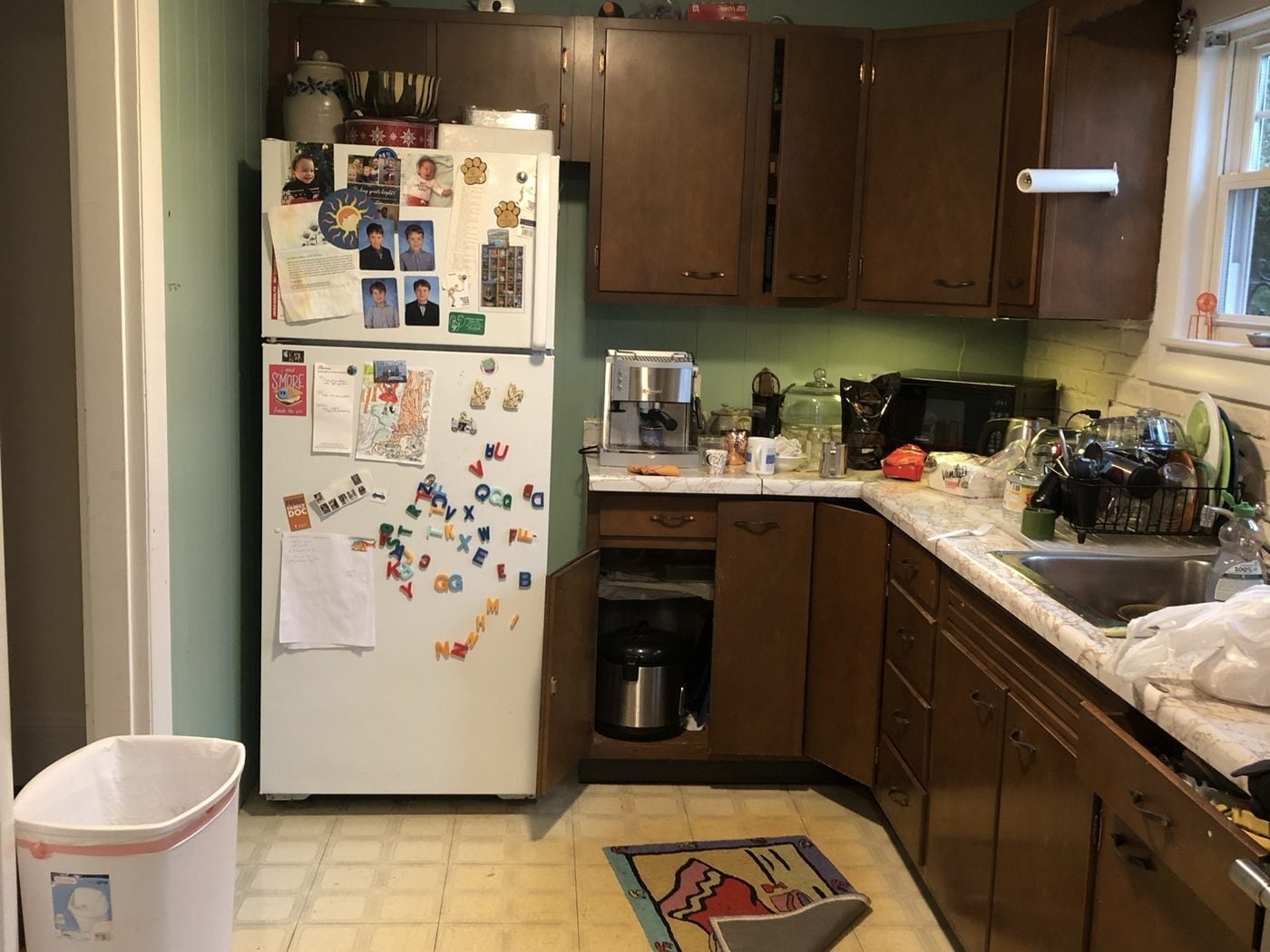 Before: Kitchen: a small L-shaped kitchen with dark cabinets and a drop ceiling became a long, bright kitchen with maple cabinets, an island and windows over the counters.