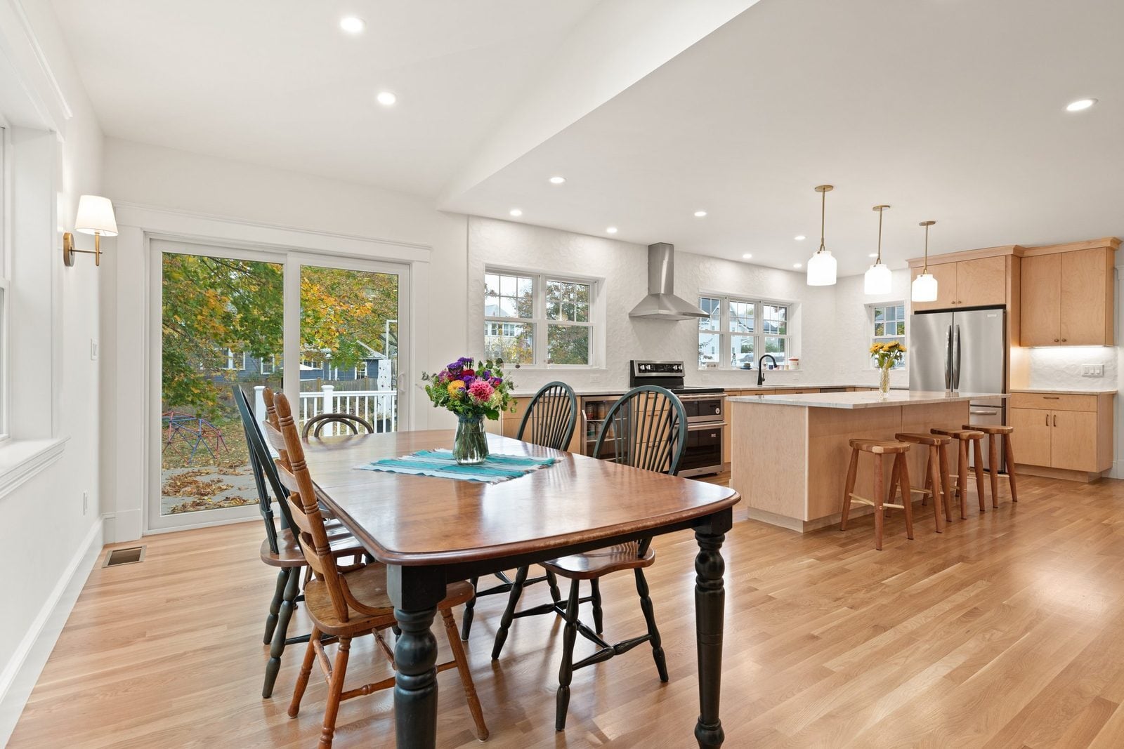 Dining area with a sliding door to the deck, open to a maple kitchen with an island and stools