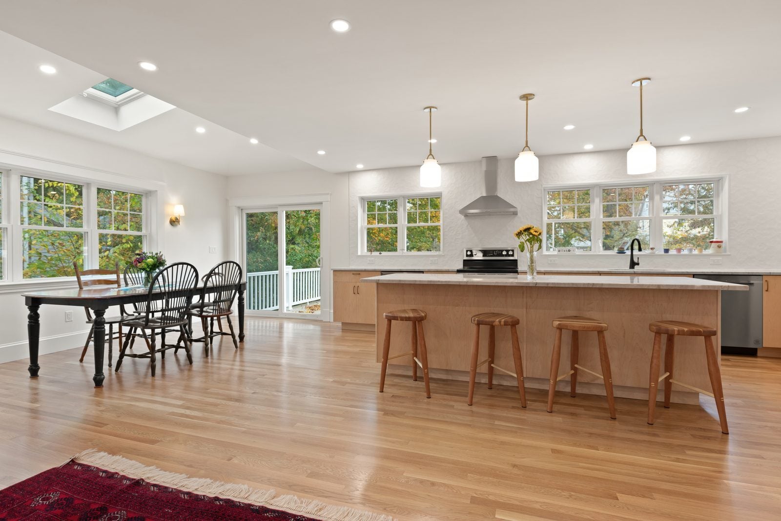 Open kitchen and dining area with oak floors, glass pendants and a skylight