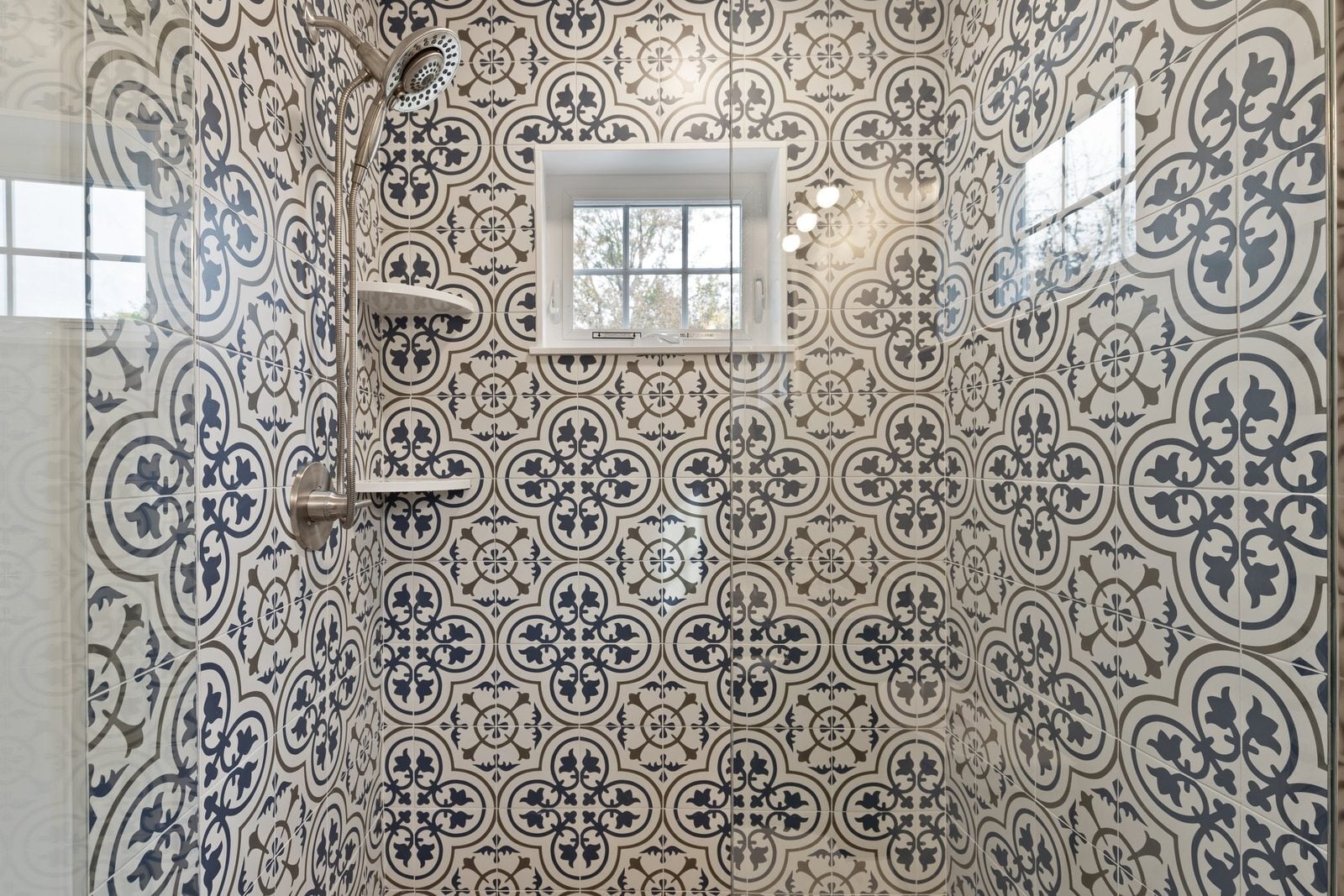Glass-enclosed shower with blue-and-white patterned tile and a small window