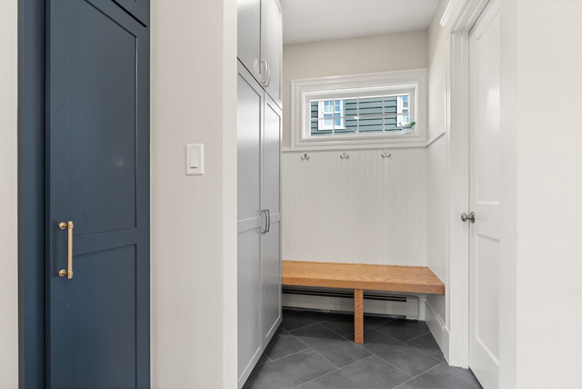 After: Back entry: a cramped back-door nook off the kitchen gave way to a mudroom in the new addition, with a bench, hooks, beadboard and tall storage.
