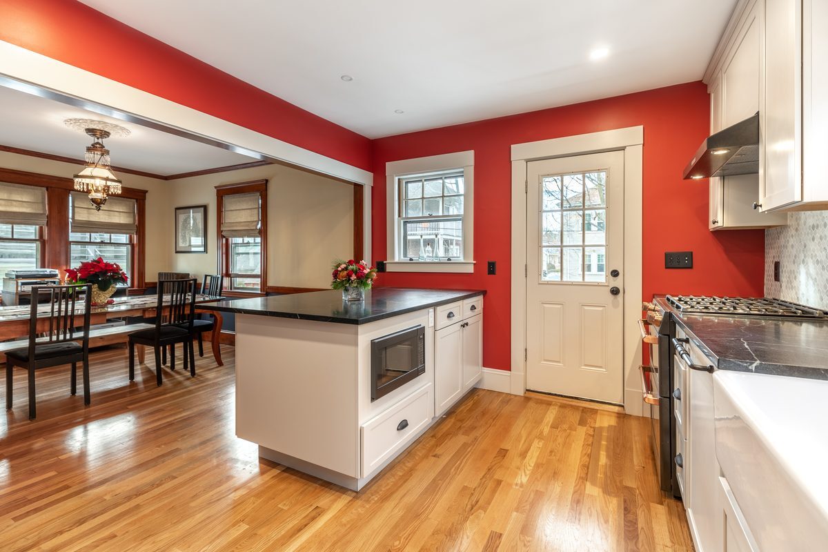 After: Kitchen to dining room: a single doorway became a wide opening with a peninsula and built-in microwave, and oak floors now run from room to room.