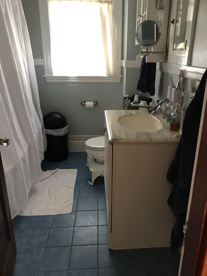 Before: Upstairs bath: the single vanity and blue tile floor gave way to a double vanity, white hex tile and a radiator recessed into the wall under the window.