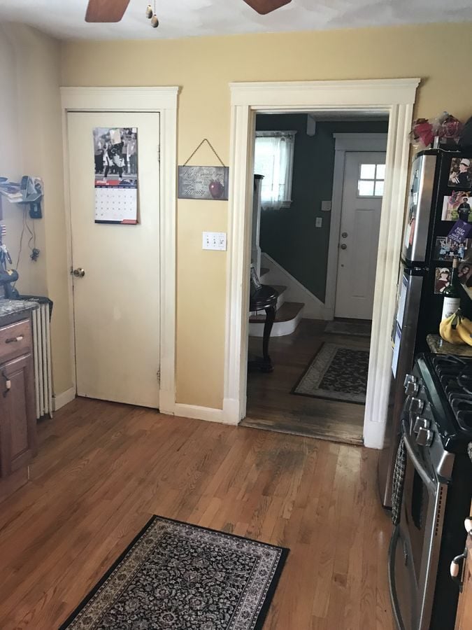 Before: Toward the front hall: the range and freestanding fridge corner became double wall ovens and a full run of white cabinets, with the pantry door and hall doorway kept in place.
