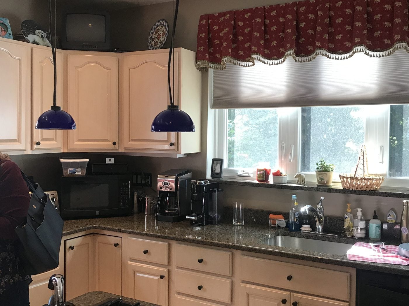 Before: Kitchen: a cooktop island and a cramped corner were replaced by a navy island, a range wall with a hood, and glass-front uppers to the ceiling.
