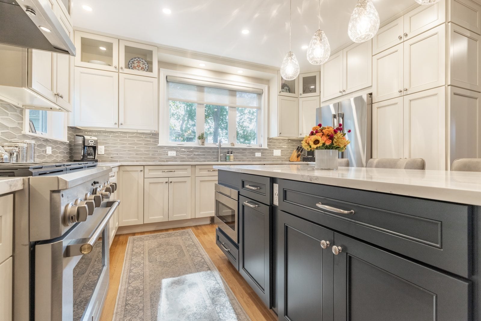 Range wall with stainless hood, gray elongated hex tile and white cabinets