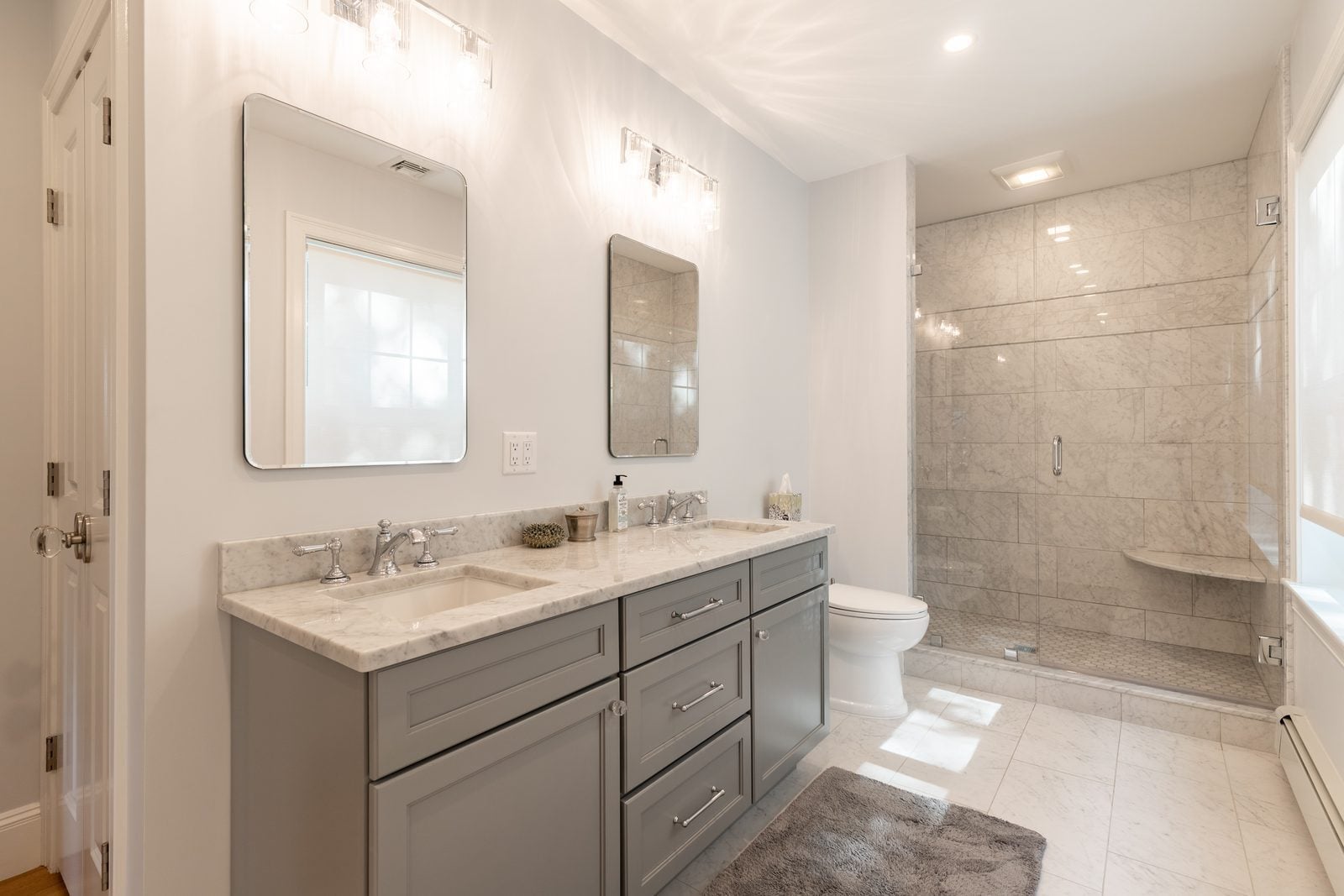 Primary bath with gray double vanity and glass walk-in shower