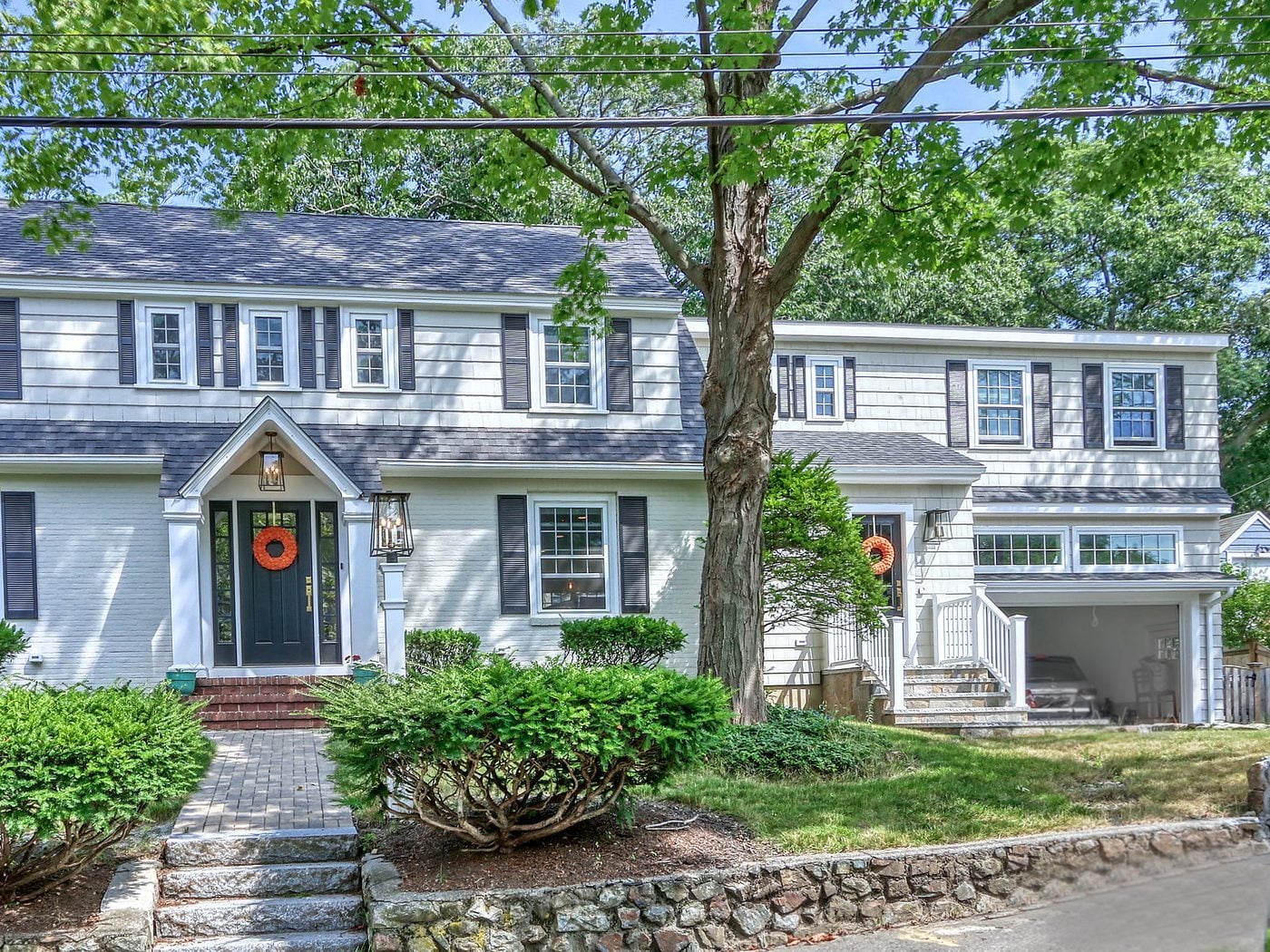After: Front: the old garage wing on a stone foundation came down and was rebuilt as a two-story addition with a garage below, a mudroom entry up granite steps, new windows and a new roof.