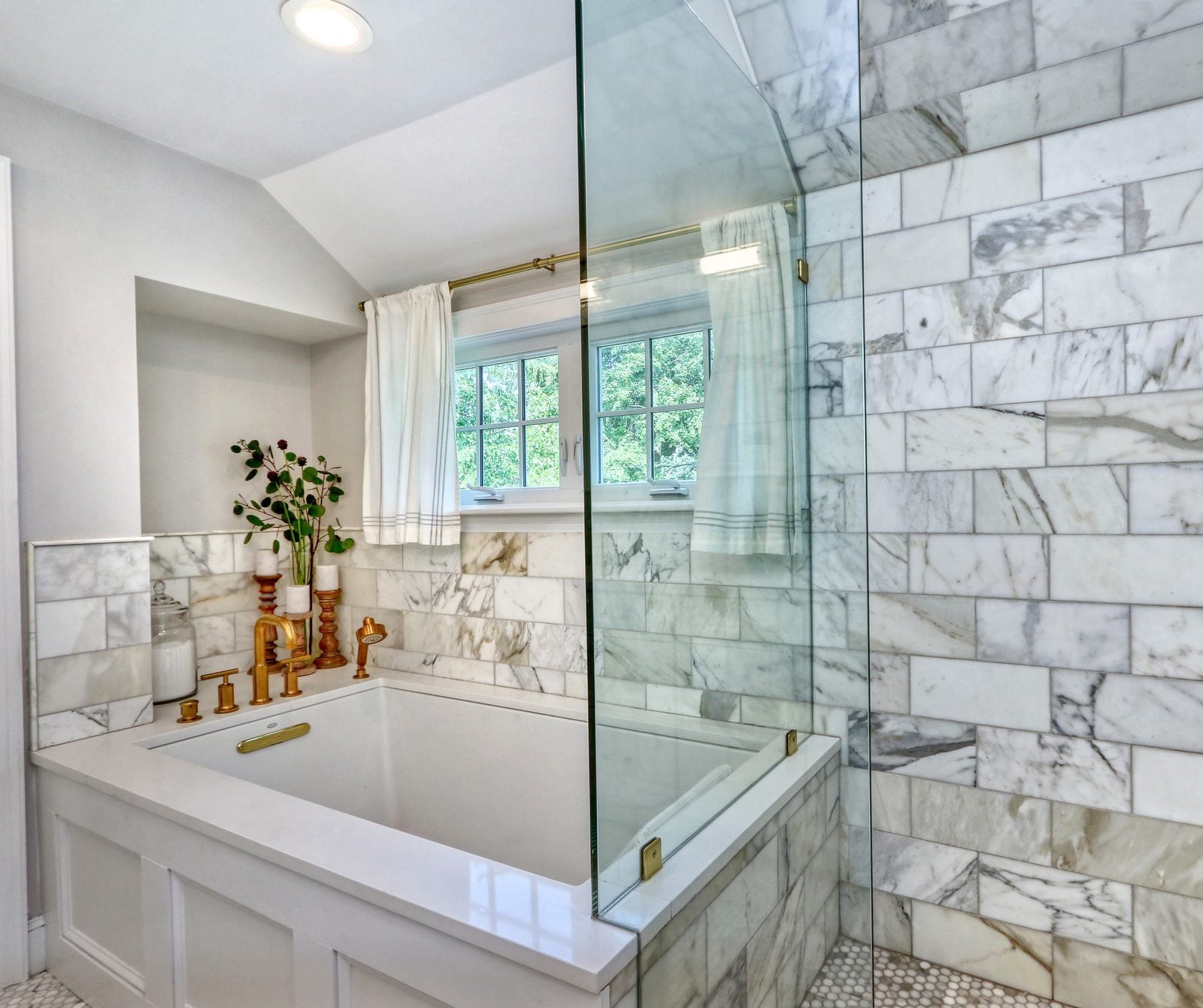 Primary bath soaking tub with a marble surround next to the glass-enclosed shower