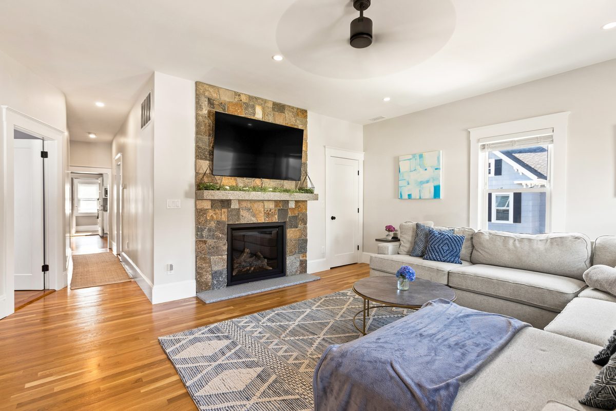 After: Family room: the radiator wall became a stone gas fireplace with a granite hearth and mantel, plus a new closet beside it.