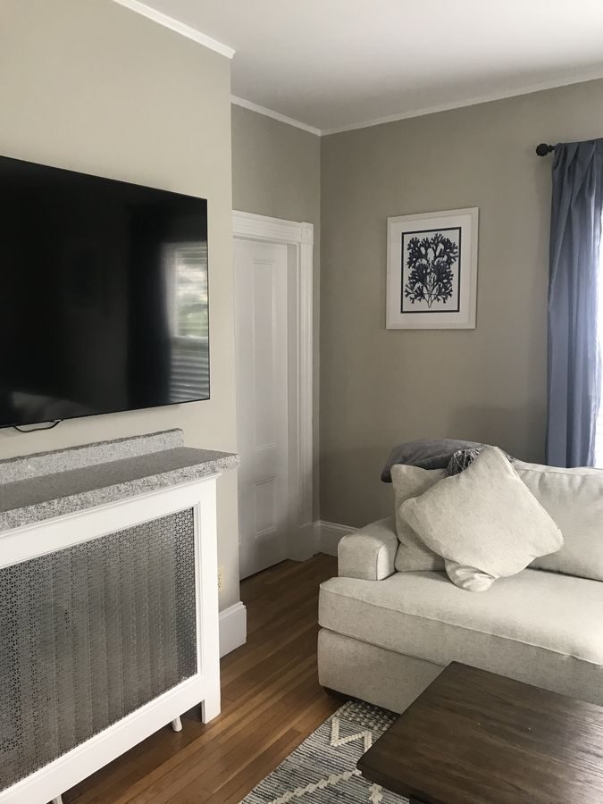 Before: Family room: the radiator wall became a stone gas fireplace with a granite hearth and mantel, plus a new closet beside it.