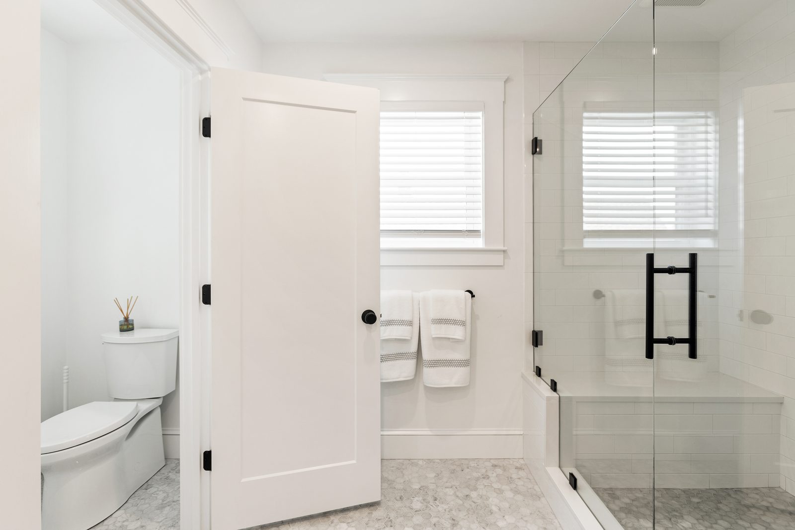Attic primary bathroom in Wakefield, MA with a frameless glass shower, white subway tile, built-in bench and separate toilet room