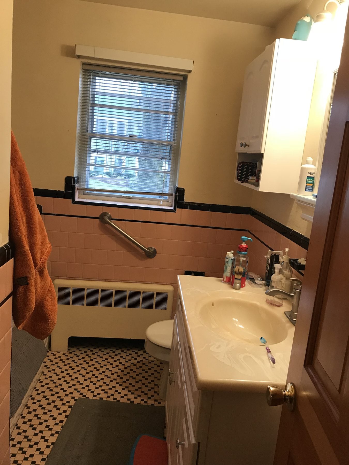 Before: Bathroom: pink and black tile and an old vanity gave way to a tiled tub surround, a wood vanity with a quartz top and a wood-look tile floor.