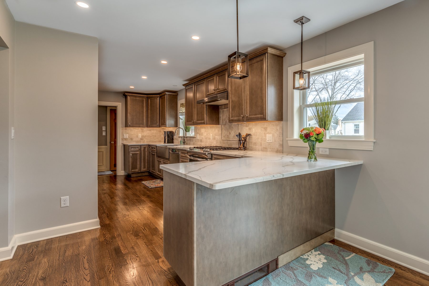 End of the kitchen peninsula with pendant lights and a view down the galley kitchen in Wakefield, MA