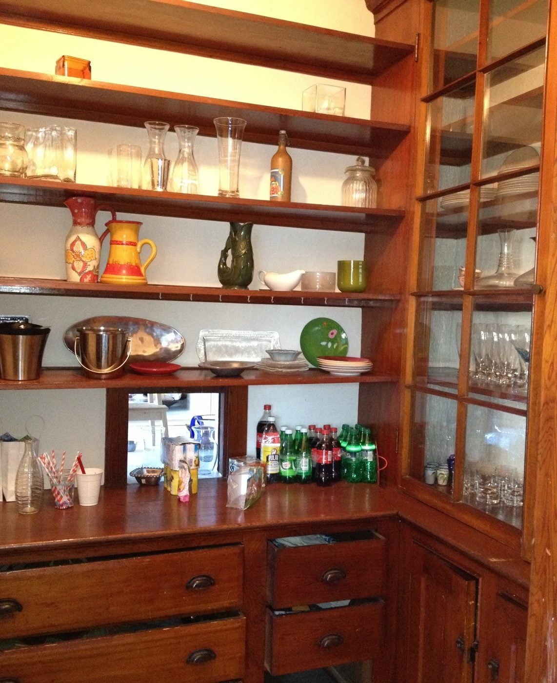 Before: Pantry: old open shelves and worn built-ins became a butler's pantry with dark cherry cabinets, leaded-glass doors and a hammered sink.