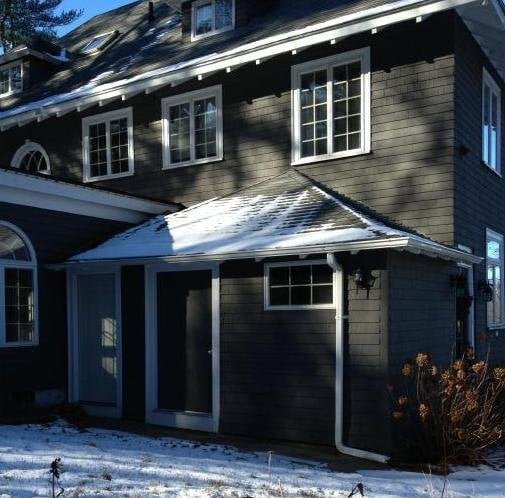 Before: Side entry: the old door under a low hip roof, and our design for the new covered porch with an arched header, square columns, stone piers and a door with sidelights.