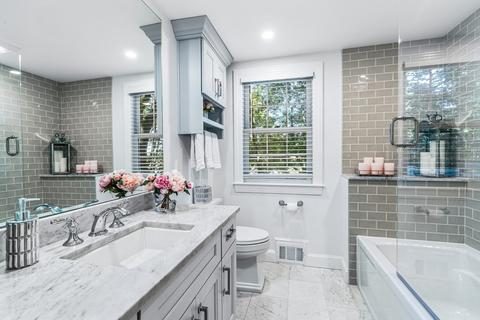 Remodeled bathroom in Winchester, MA with gray subway tile, a marble-top vanity, wall cabinet and glass-panel tub