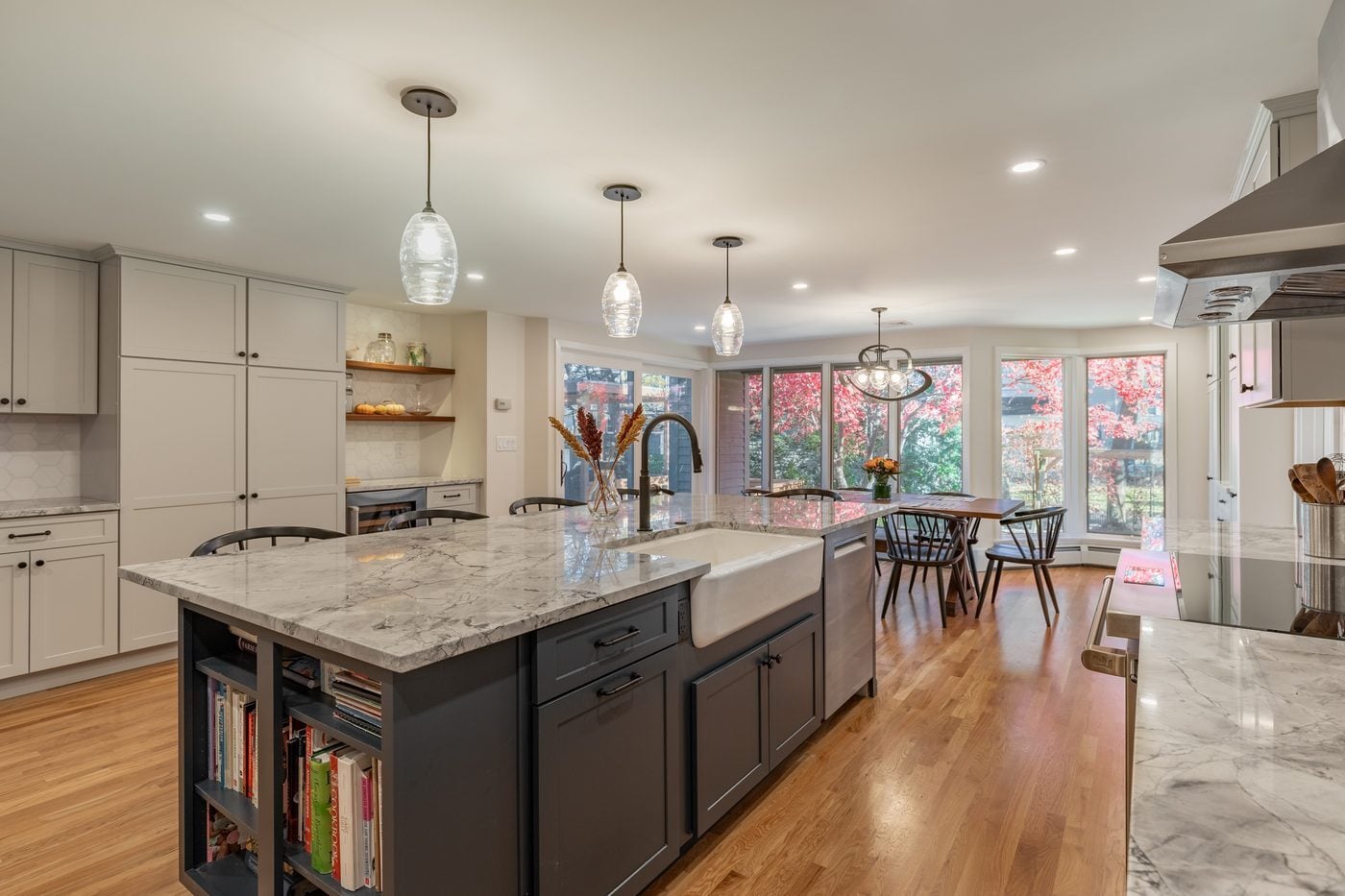 After: Kitchen: the closed L-shaped oak kitchen with a pass-through opened up around a long charcoal island with a farmhouse sink.
