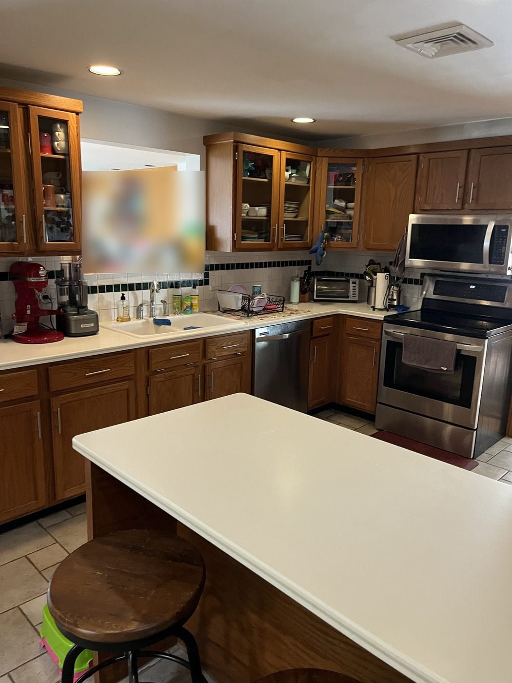 Before: Kitchen: the closed L-shaped oak kitchen with a pass-through opened up around a long charcoal island with a farmhouse sink.