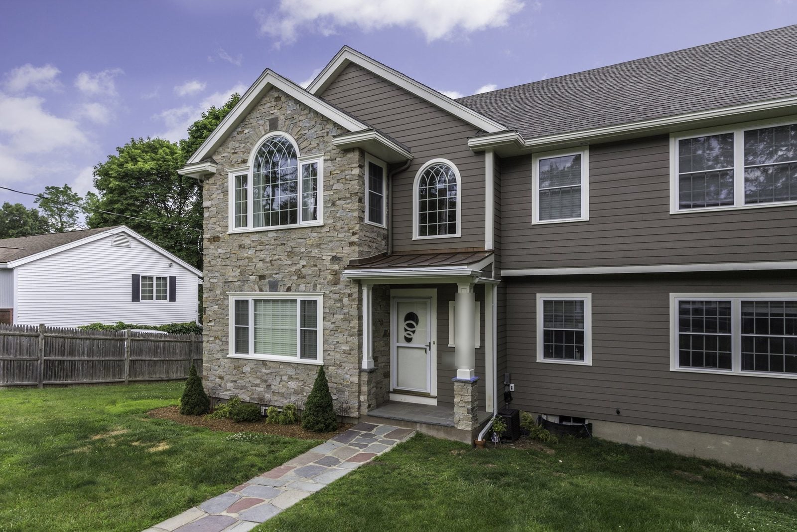 Front entry with copper standing-seam roof, square columns and stone veneer gable with arched window in Winchester, MA